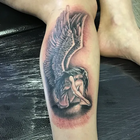 Tatuaje black and grey de un ángel con las alas extendidas en el brazo.