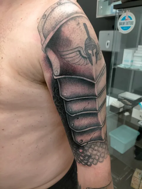 Tatuaje black and grey de una armadura en el hombro.