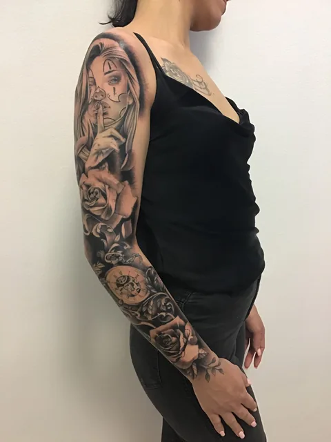 Tatuaje black and grey de una chicana con rosas en el brazo, vista lateral.