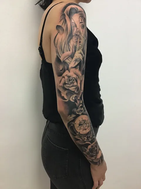 Tatuaje black and grey de una chicana con rosas en el brazo, vista posterior.