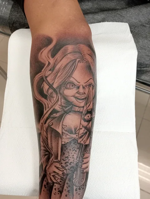 Tatuaje black and grey de Chucky en el antebrazo.