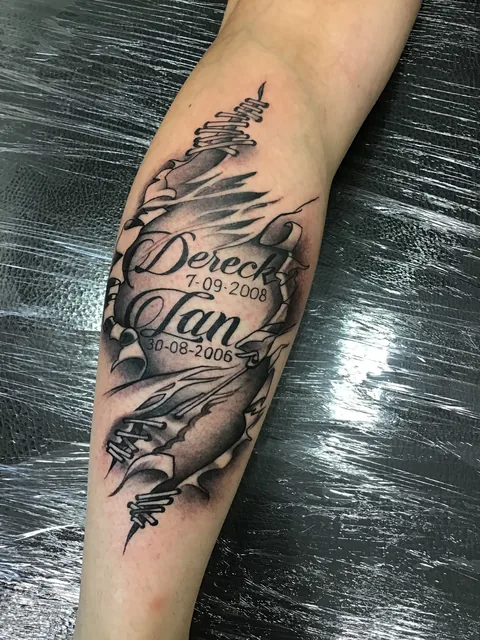 Tatuaje conmemorativo con texto, fecha y pluma en black and grey.