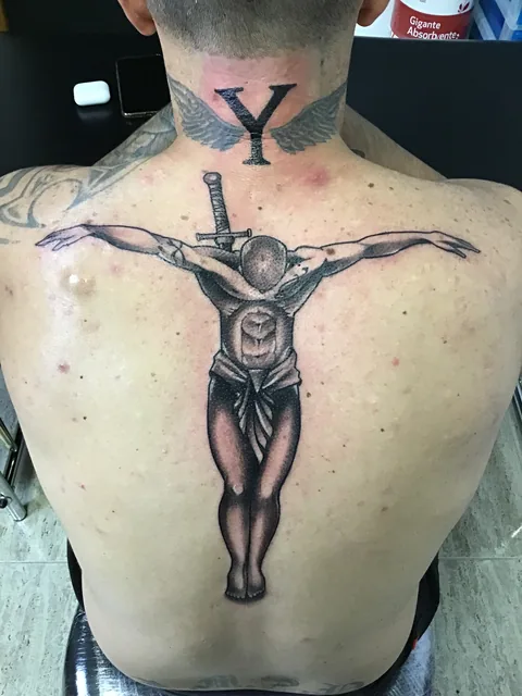 Tatuaje black and grey de un crucifijo en la espalda.