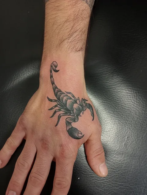 Tatuaje blackwork de un escorpión sobre la mano.