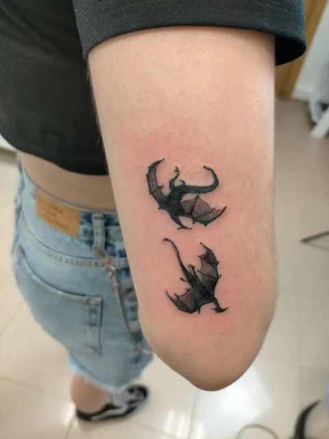 Tatuaje blackwork de dos gatos en silueta en el brazo.