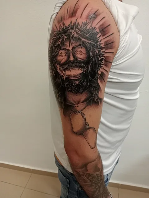 Tatuaje black and grey de Jesús con corona de espinas en el brazo.