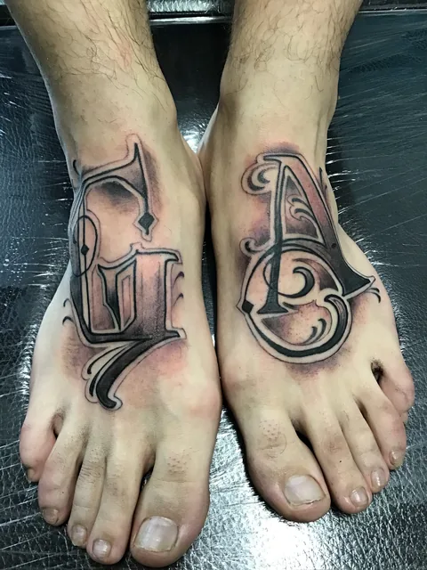 Tatuajes lettering de iniciales en ambos pies.