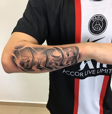 Tatuaje lettering del número 99 en el antebrazo.