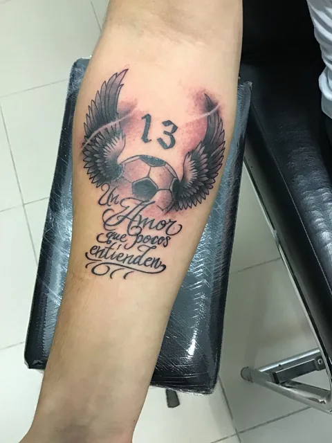 Tatuaje memorial black and grey con calavera y alas en el antebrazo.