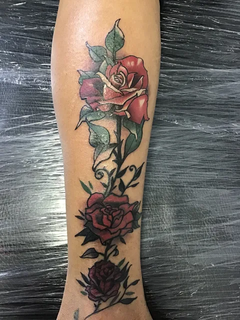 Tatuaje neotradicional de rosas rojas en el antebrazo.
