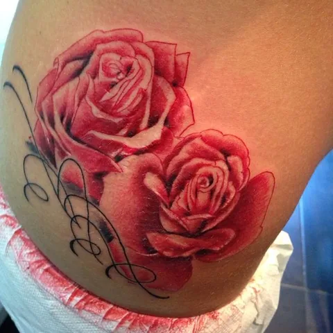 Tatuaje neotradicional de rosas rojas en el costado.