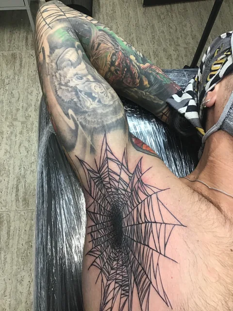 Tatuaje blackwork de una telaraña geométrica en el pecho.