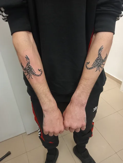 Pareja de tatuajes blackwork de escorpiones en los brazos.